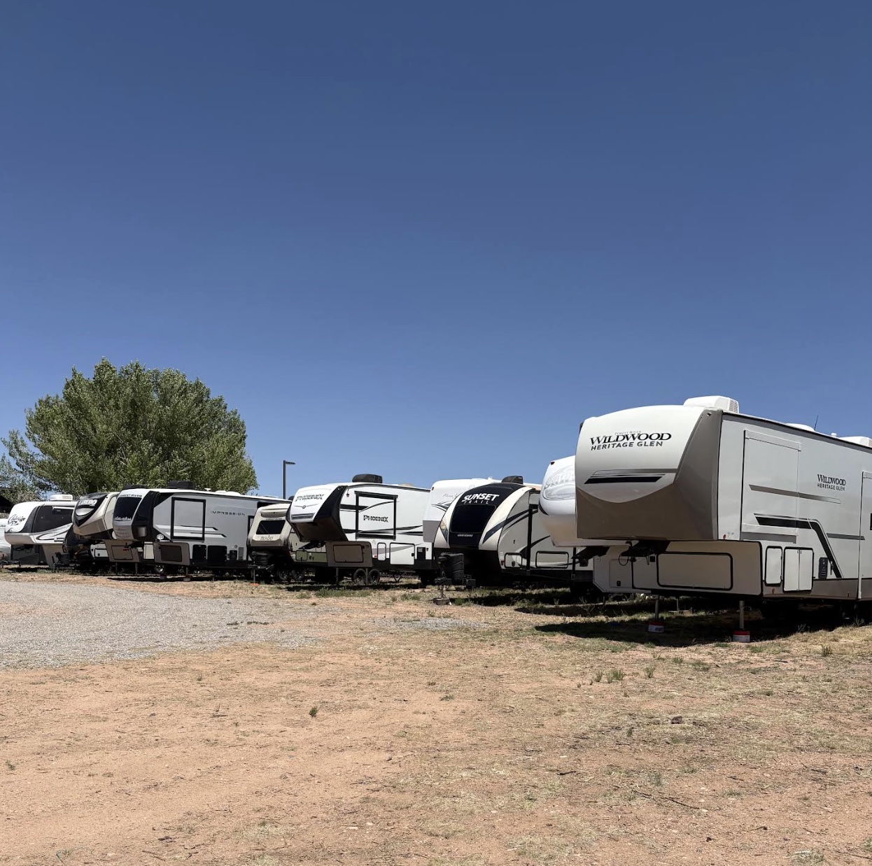 A row of RVs and 5th-wheel trailers stored on the lot in Santa Fe, NM